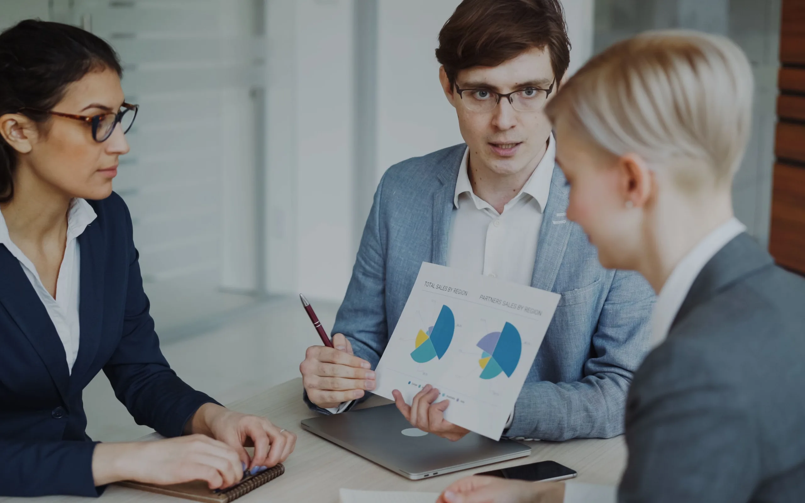 Une équipe de commerciaux étudie des graphiques de ventes pour préparer un plan de prospection dans un bureau lumineux